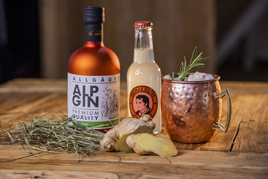In seiner kupfernen Flasche wird der AlpGin Heu neben einer Flasche Spicy Ginger und einem Stück Ingwer präsentiert.