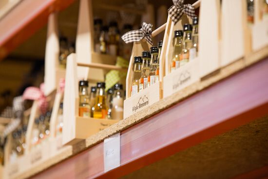 Regal befüllt mit kleinen Holztragerln, die mit Schnapsfläschchen befüllt sind.