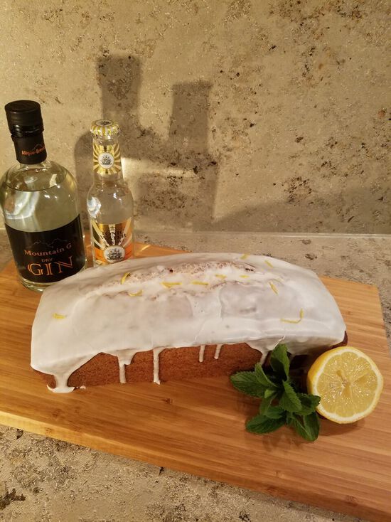 Die Flasche Mountain G Dry Gin steht neben dem kastenförmigen Gin-Tonic-Kuchen, der mit Zuckerguss überzogen wurde.