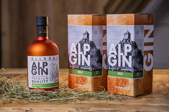 Der AlpGin Heu auf rustikalem Holztisch und dekoriert mit grünem Heu